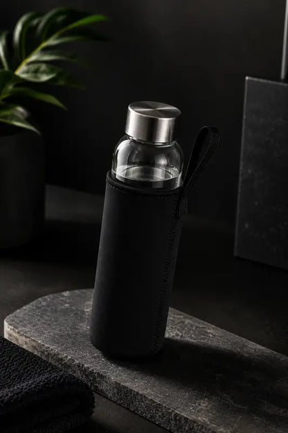 Glass water bottle with black sleeve on a dark surface