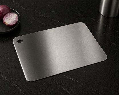 Stainless steel cutting board on a dark surface with red onions in the background